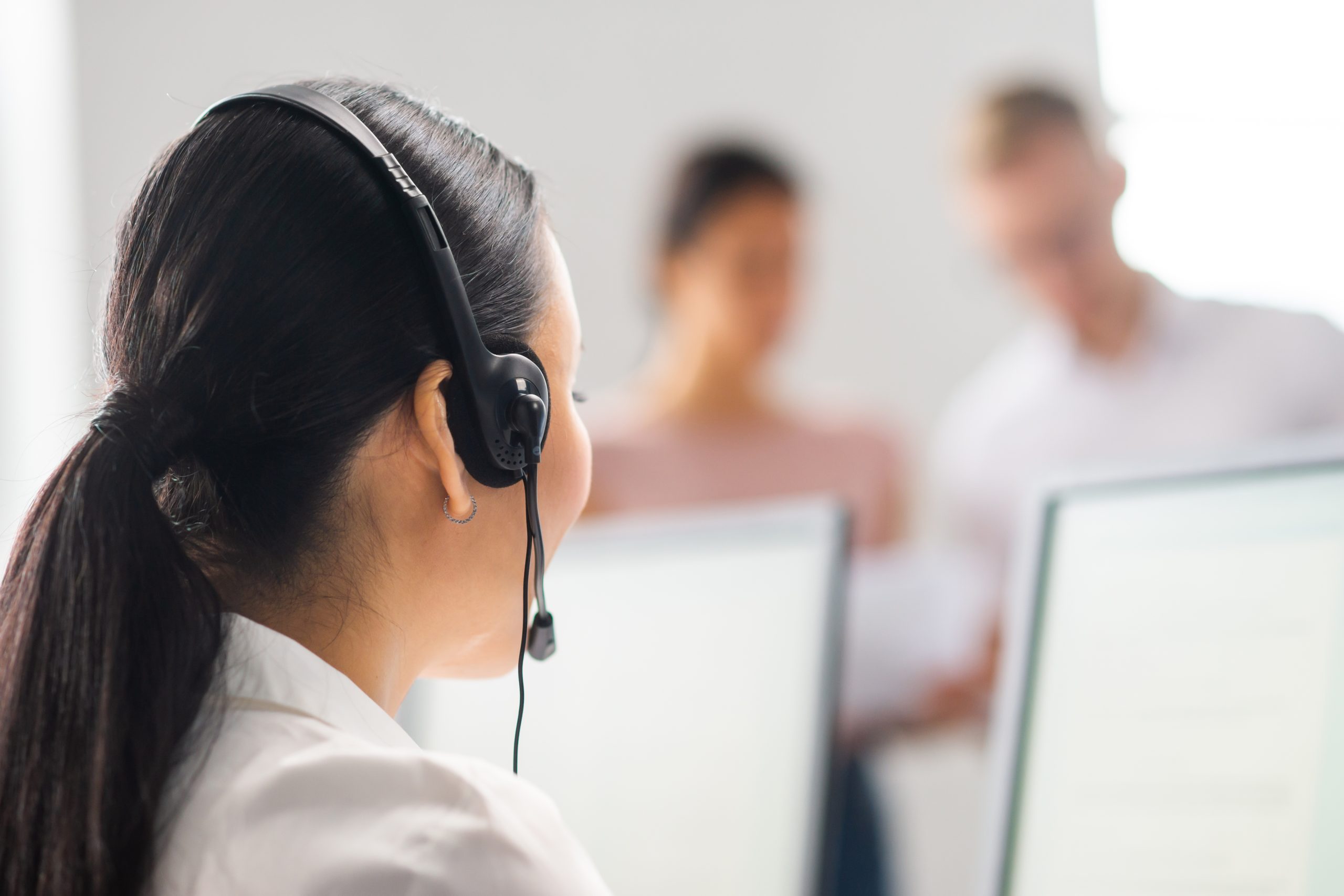 Frau mit Headset sitzt vor PC, Servicemitarbeiterin, Support-Team
